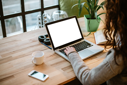 Woman working on laptop with white screen in modern office.
